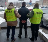 Policjanci prowadzą zatrzymanego sprawcę.