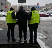 Policjanci prowadzą zatrzymanego sprawcę.