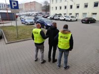 Policjanci prowadzą zatrzymanego mężczyznę.