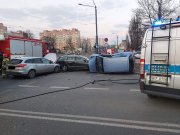 Miejsce kolizji drogowej, rozbite pojazdy i radiowozy służb.