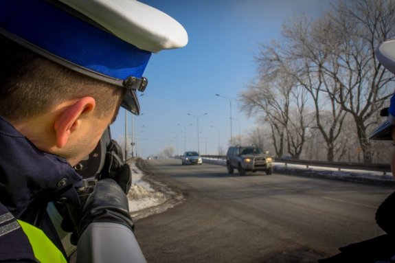 Policjant ruchu drogowego mierzy prędkość jadącym pojazdom