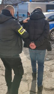 Policjant prowadzi zatrzymanego sprawcę.