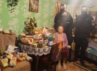 Policjanci Komendy Miejskiej Policji w Łodzi przekazują seniorce artykuły żywnościowe i środki czystości.