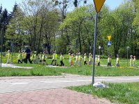 dzieci idą w parze, ćwiczą z policjantkami przechodzenie przez pasy, oraz dowiadują się, co oznaczają pionowe znaki drogowe