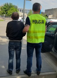 Policjant prowadzi zatrzymanego sprawcę.