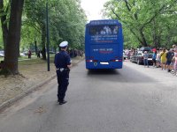 Policjant stojąc za autokarem sprawdza stan techniczny oświetlenia.