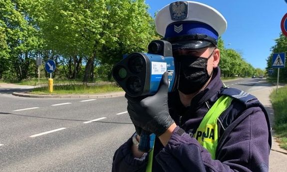 Policjant w maseczce trzymający fotoradar.