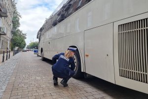 Umundurowana policjantka Wydziału Ruchu Drogowego Komendy Miejskiej Policji sprawdza stan techniczny autokaru.