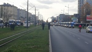 Radiowozy policyjne i policjanci podczas zabezpieczenia przemarszu kibiców ulicami miasta.