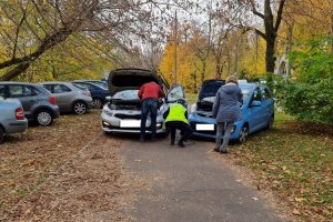 Miejsce unieruchomienia samochodu, policjantka wraz mężczyzną podpinają kable. Obok stoi właścicielka auta.