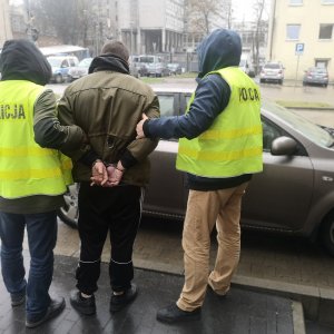 Zatrzymany prowadzony przez nieumundurowanych policjantów.