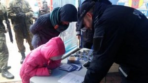 na stoisku policyjnym dwaj policjanci w mundurach nachylają się na dziećmi