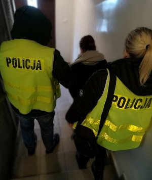 Zatrzymana kobieta za rozbój sprowadzana po schodach przez policjantów.