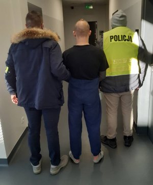 Policjanci prowadzą zatrzymanego sparawcę rozboju