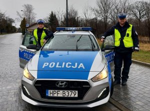 Policjanci stoją przy radiowozie.