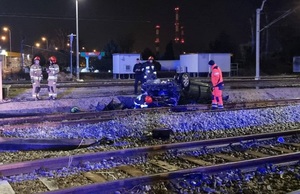 Miejsce zdarzenia przy rozbitym samochodzie policjanci i inne służby.