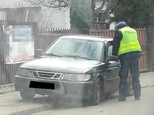 Policjant stoi przy samochodzie sprawcy.