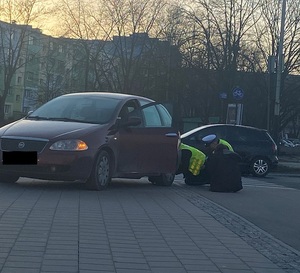 Policjanci naprawiają samochód kobiety.