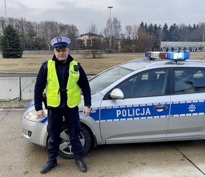 Policjant ruchu drogowego stoi przy radiowozie.