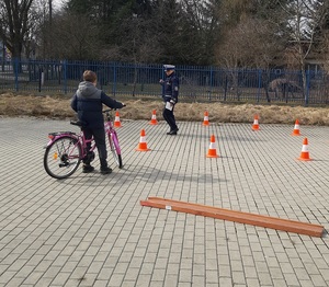 Policjantka ocenia poprawność jazdy ucznia.