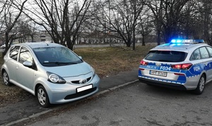 Pojazd uczestniczący w zdarzeniu drogowym i oznakowany radiowóz stoją na parkingu.