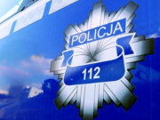 Odznaka policyjna na drzwiach radiowozu z napisem policja i numerem 112.