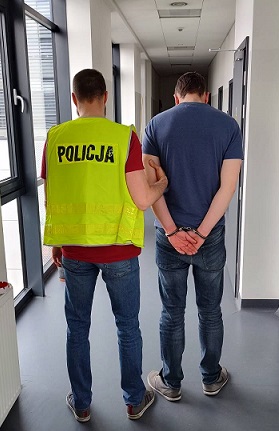 Zatrzymany prowadzony przez policjanta korytarzem komisariatu.