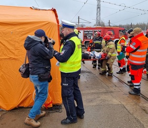 Policjant ogranicza dostęp osób postronnych do namiotu medycznego.