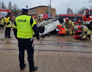 Uczestnicy podczas symulacji katastrof. Ratownicy i strażacy udzielają pomocy osobom zakleszczonym w przewróconym na dach samochodzie.