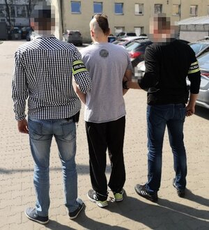 nieumundurowani policjanci prowadzą zatrzymanego mężczyznę