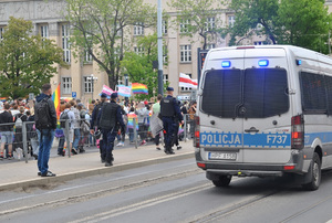 Pochód ulicami miasta Marszu Równości. Na zdjęciu policjanci przy radiowozie policyjnym.