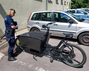 Policjantka stoi przy odzyskanym rowerze.