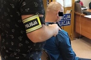 Zatrzymany sprawca kradzieży kieszonkowych jest pilnowany przez policjanta.