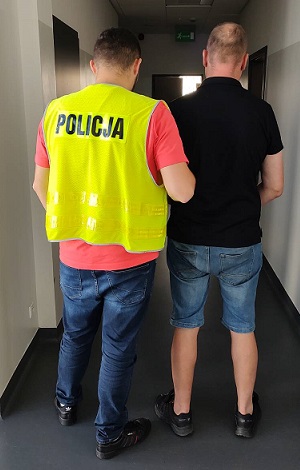 Policjant prowadzi sprawcę rozboju.