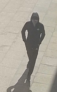 mężczyzna ok. 175cm wzrostu, sylwetka szczupła, ubrany na czarno – spodnie czarne, bluza z kapturem czarna, na głowie czarna czapka z daszkiem oraz kaptur od bluzy
