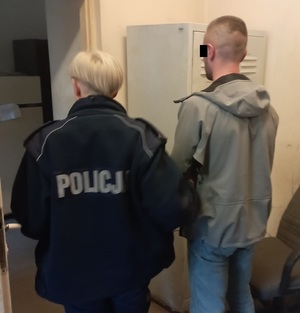 Policjantka prowadzi zatrzymanego sprawcę.