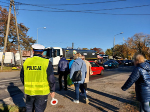 Policjant nadzoruje bezpieczne przejście w rejonie cmentarza.