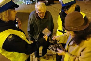 Seniorzy pokazują swoje zdjęcia policjantom.