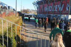 Zabezpieczenie meczu, kibice gości wchodzą na stadion, w tle umundurowani policjanci.