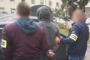 Policjanci prowadzą podejrzanego do radiowozu.
