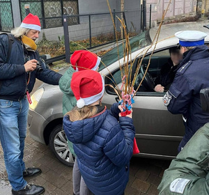 Dzieci rozmawiają z kierowcą siedzącym w aucie.