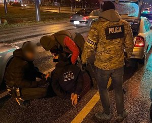 Policjanci zatrzymują sprawców kradzieży katalizatorów na ulicy.