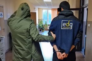 Policjant prowadzący zatrzymanego na terenie komisariatu.