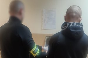 Policjant pobiera od zatrzymanego odbitki linii papilarnych.