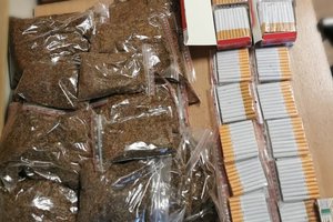 Papierosy i tytoń spakowany w torebkach leża na stole.