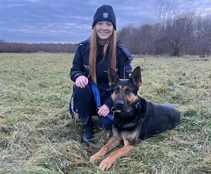 Policjantka w mundurze z psem służbowym.