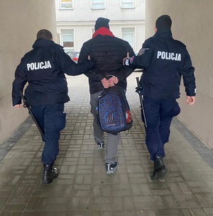 Policjanci prowadzą zatrzymanego sprawce kradzieży.