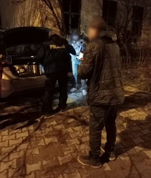 Policjant rozdaje zupę, karimaty i śpiwory osobom potrzebującym.