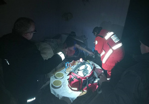 Policjant i ratownik medyczny udzielają pomocy medycznej osobie bezdomnej.