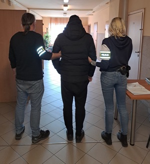 Policjanci prowadzą podejrzanego korytarzem komisariatu